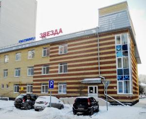 um grande edifício com carros estacionados em frente em Hotel Zvezda em Tiumen