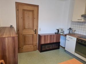 a kitchen with a wooden door and a white appliance at Herzensplatzl in Pfaffenhofen