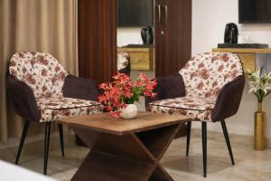 two chairs and a table with a vase of flowers at Saffron Inn - Near India Expo Mart in Greater Noida