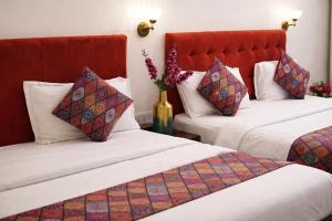 a hotel room with two beds and a vase of flowers at Saffron Inn - Near India Expo Mart in Greater Noida +34 photos
