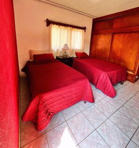 a bedroom with two beds with red sheets at La prieta linda in Tamasopo