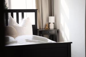 a bed with white pillows and a lamp on a table at Boutique Suite Hannah in Bautzen
