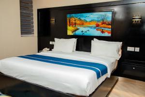 a bedroom with a large bed with a painting on the wall at Spring Hills Group in Dodoma