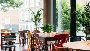 a restaurant with tables and chairs and a large window at Ruby Zoe Hotel London by IHG in London +75 photos