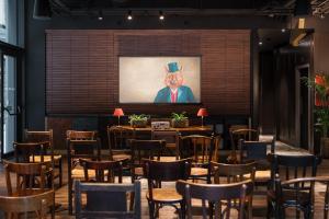 a restaurant with tables and chairs and a painting of a gentleman at Ruby Stella Hotel London by IHG in London