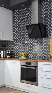 a kitchen with white cabinets and a black wall at MoMa Homes Kecskemét in Kecskemét