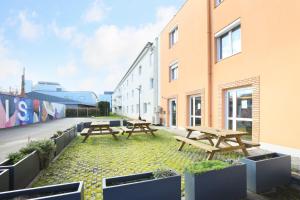 two picnic tables on the side of a building at Sweetly Isatis Mérignac Hôtel de ville in Mérignac