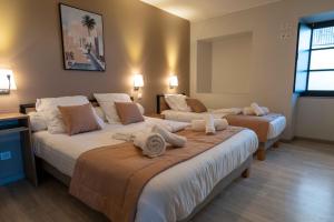 a hotel room with three beds with towels on them at Auberge du Cezallier in Montgreleix