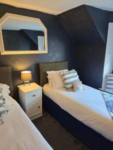 two twin beds in a room with a mirror at Harbour Moon Inn in Looe +7 photos