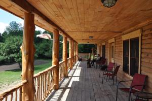 a wooden porch with chairs and an umbrella at Lodge Solange in Palatine Bridge
