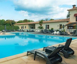 a swimming pool with two lounge chairs in front of a building at Villa de l Eyre in Salles