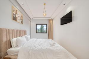 a bedroom with a white bed and a tv at JASMINe in Marrakesh