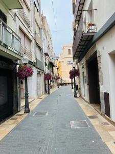 an empty street in a city with buildings and flowers at HAVELI Vinaros in Vinarós