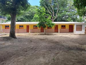 a yellow building with a tree in front of it at Hospedaje Mango y Mar Habitaciones in Coveñas