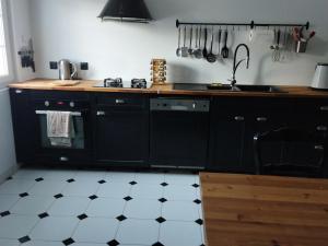 a kitchen with black cabinets and a stove top oven at Les Lilas in Saint-Clair