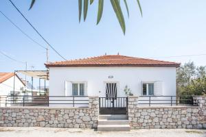 a white house with a stone wall at Filerimos House in Ialysos