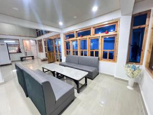 a living room with a couch and a table and windows at YNL HOMESTAY a boutique hotel in Dirang Dzong