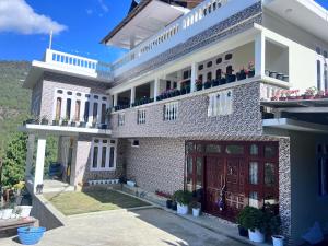 a large white brick house with potted plants at YNL HOMESTAY a boutique hotel in Dirang Dzong