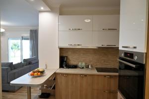 a kitchen with white cabinets and a table with a bowl of fruit at Thea Hill in Kritharia
