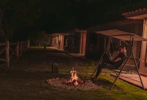 a man sitting in a chair next to a fire at Tara Vegan Lodge - Sacred Valley in Urubamba