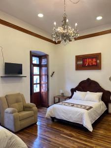 a bedroom with a bed and a chair and a chandelier at Rossa Mia Hotel Boutique in Quito