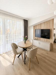 a living room with a table and chairs and a tv at Apartamenty Lipowa in Puck