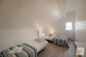 two beds in a room with white walls and wood floors at La Cabane à Hirel in Hirel