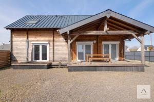 a wooden cabin with a bench on a porch at La Cabane à Hirel in Hirel