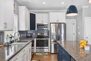 a kitchen with white cabinets and stainless steel appliances at 5 BR Poolside Paradise Just Steps from the Beach in Ocean Isle Beach