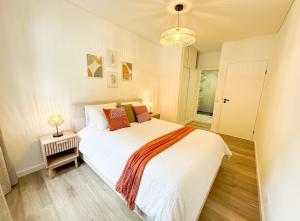 a bedroom with a large white bed and a lamp at Ninho da Ribeira in Ribeira Brava