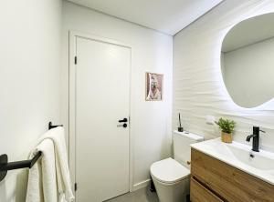 a white bathroom with a toilet and a sink at Ninho da Ribeira in Ribeira Brava +15 photos