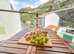 a plate of fruit on a table with a bottle of wine at Ninho da Ribeira in Ribeira Brava