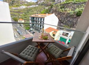 a balcony with a table and chairs and a view at Ninho da Ribeira in Ribeira Brava