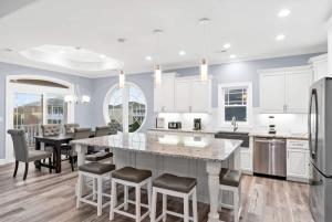 a kitchen with white cabinets and a large island with bar stools at East End Views in Ocean Isle Beach