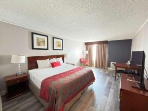 a hotel room with a bed and a desk and a television at Ramada by Wyndham Vineland Millville Area in Vineland