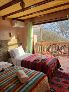 two beds in a room with a balcony at auberge atlas tamatertt in Imlil