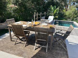 a wooden table with four chairs next to a pool at VILLA VUE MER sur la presqu'ile de GIENS in Hyères