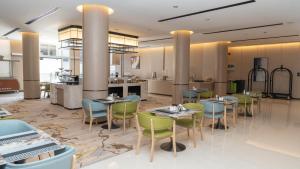 a restaurant with tables and chairs and a kitchen at Rosa Grand Hotel Granada in Riyadh