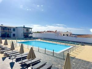 a large swimming pool with chairs and umbrellas at NextGen Casa Pepa I Terrace & Pool Fuerteventura in Costa de Antigua