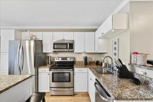 a kitchen with white cabinets and a stainless steel refrigerator at Castle By The Sea Beach Front Condo in Ocean Isle Beach