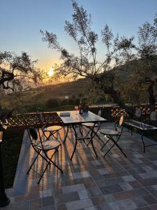 a table and chairs on a patio with the sunset at la Tana di Luna in Adrano