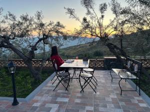 a woman sitting at a table on a patio at la Tana di Luna in Adrano