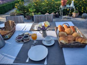a table with a basket of bread and glasses of orange juice at Dielpenhof in Zedelgem