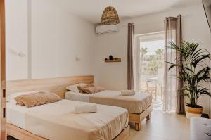 a bedroom with two beds and a potted plant at Indigo Seaside Experience in Adelianos Kampos