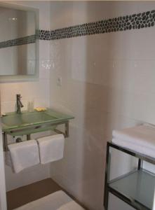 W łazience znajduje się umywalka, lustro i ręczniki. w obiekcie Hotel Le Suroit w mieście Perros-Guirec