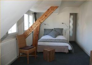 - une chambre mansardée avec un lit et une chaise dans l'établissement Hotel Le Suroit, à Perros-Guirec