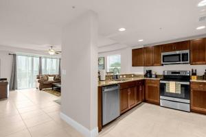 a kitchen with wooden cabinets and a living room at Beachfront Condo with Spacious Balcony in Daytona Beach