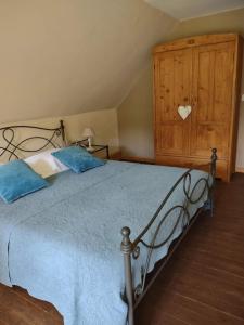 a bedroom with a bed with blue pillows and a wooden cabinet at Dielpenhof in Zedelgem