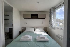 a bedroom with a bed with two towels on it at Mobilhome L'Instant Vacances - La Plage in Mimizan-Plage +10 photos