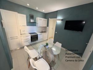 a kitchen with white chairs and a table and a tv at The Smerald in Alghero +5 photos